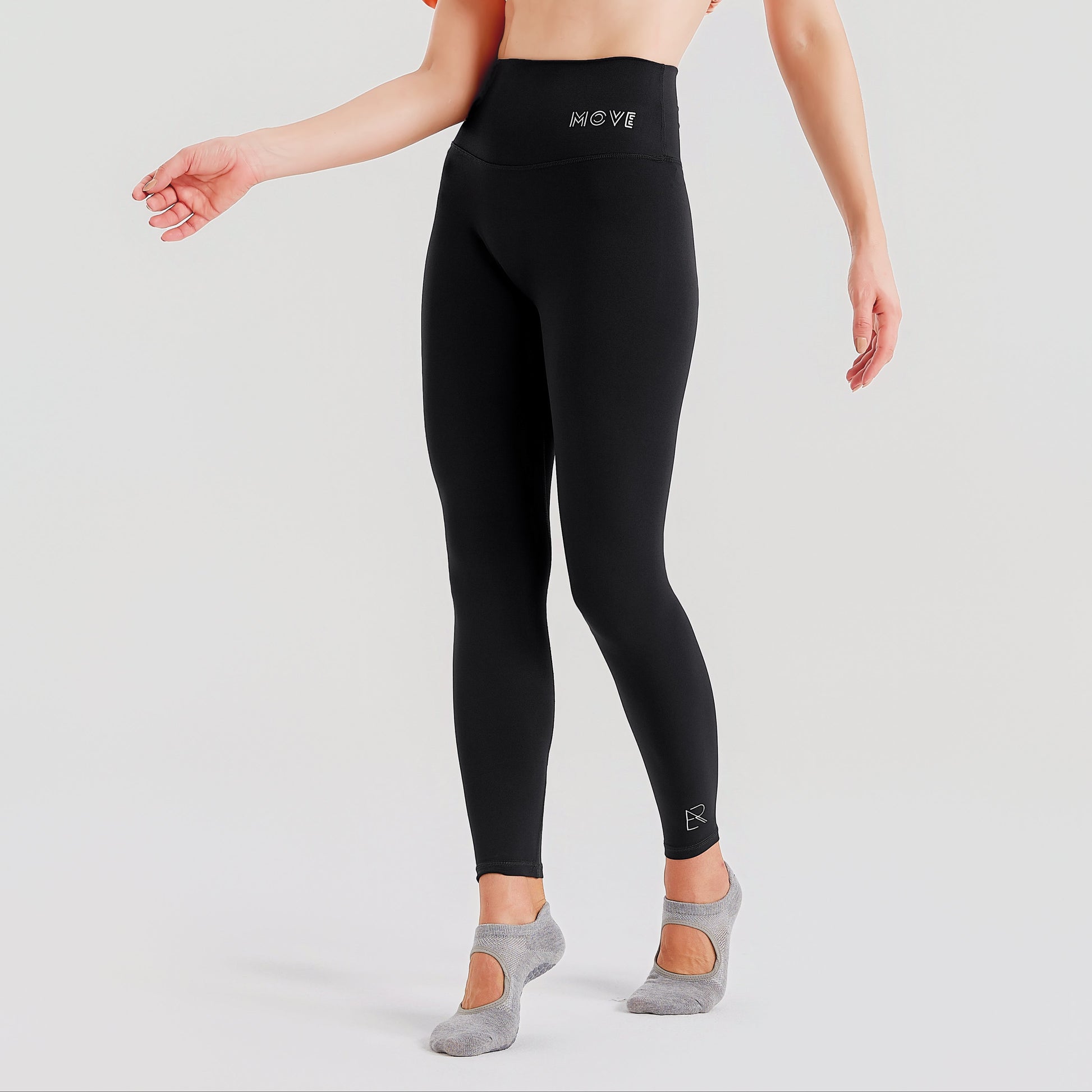 Person wearing black leggings with a visible brand logo on a light gray background